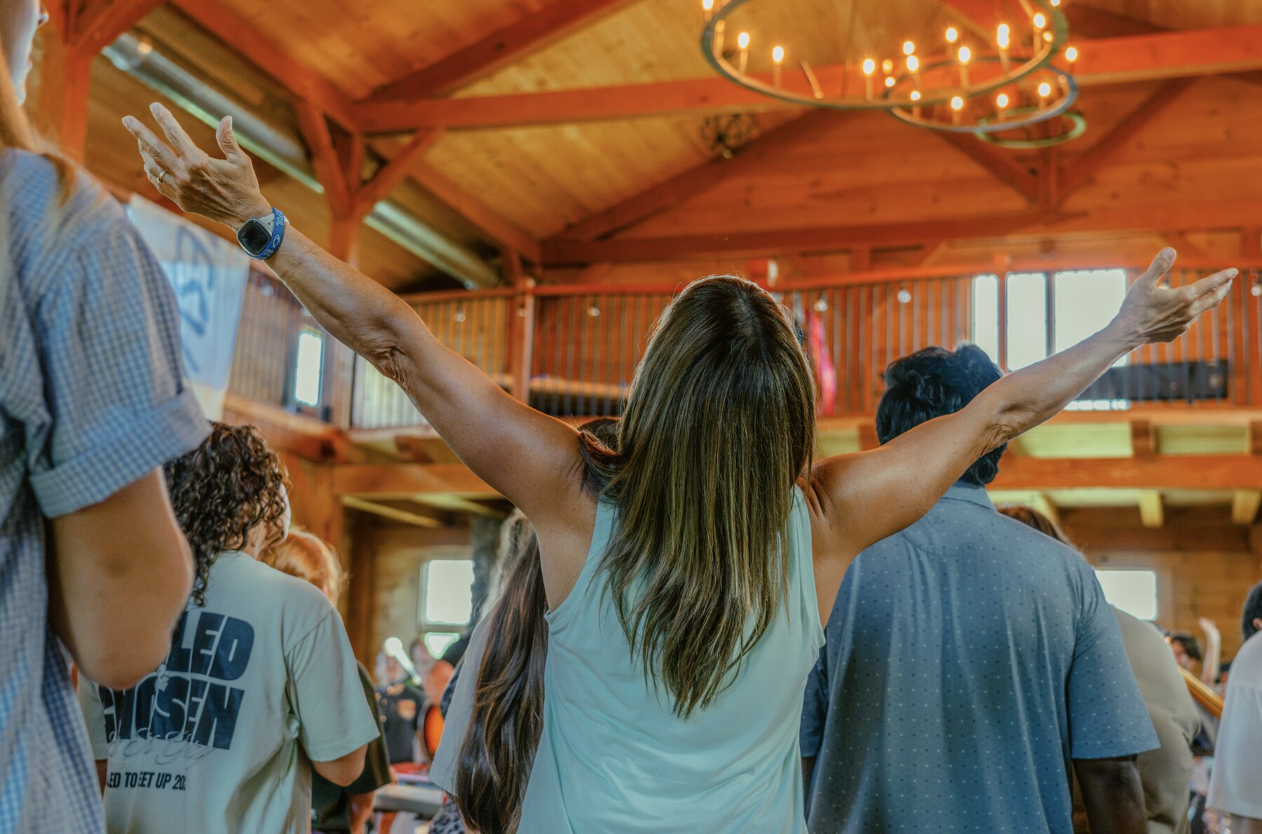 A woman raising both arms in worship among the Jesus Place Missouri gathering