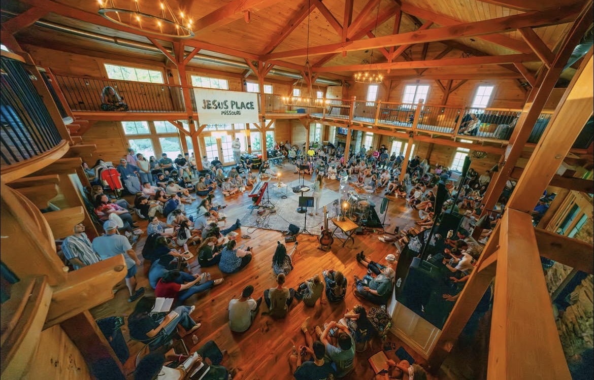 A wide view of the Jesus Place community gathered throughout a wooden lodge