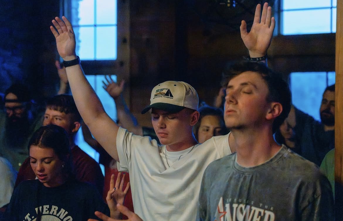 Young adults praying with eyes closed and hands raised