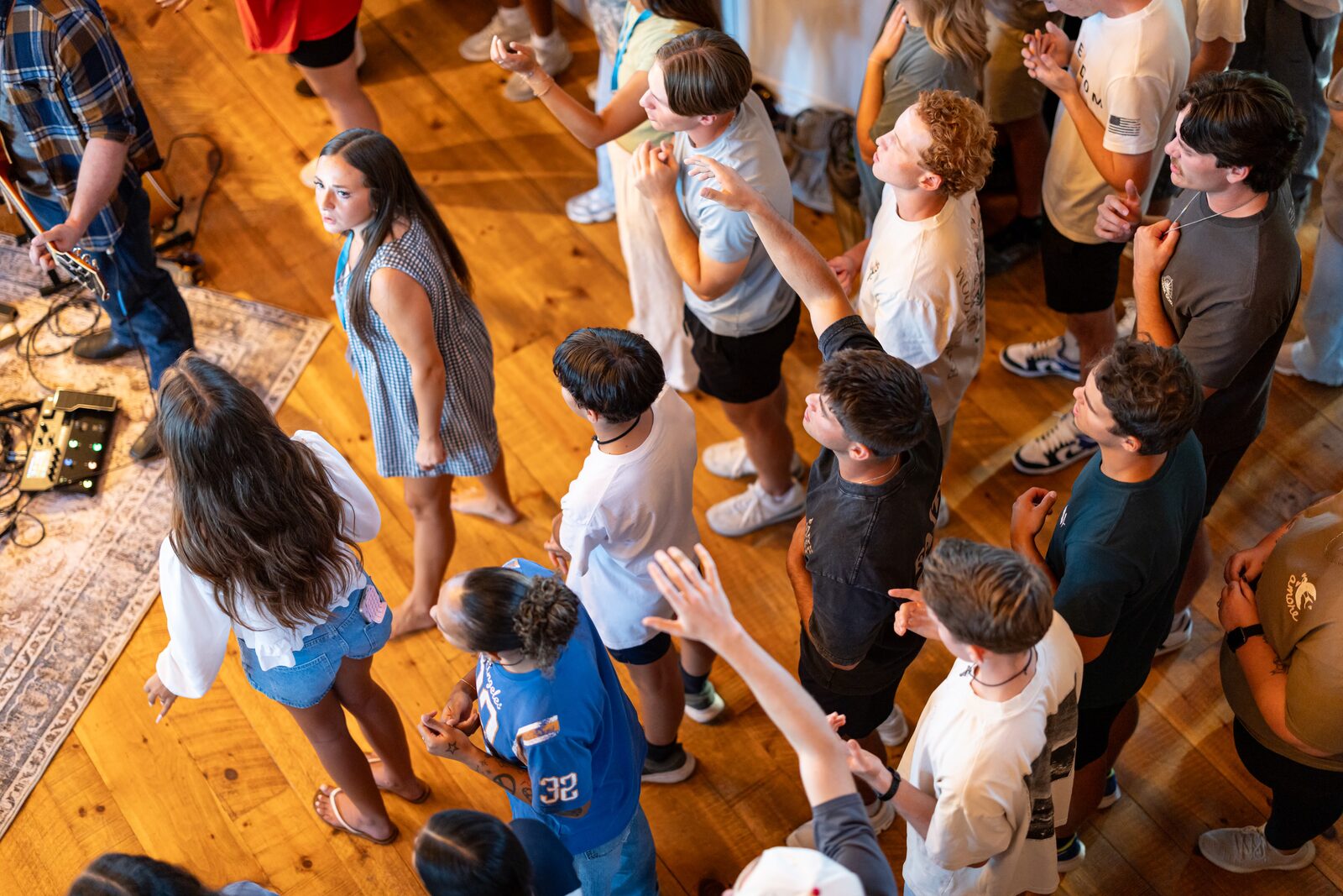 An overhead view of students standing and worshiping while a guitarist leads