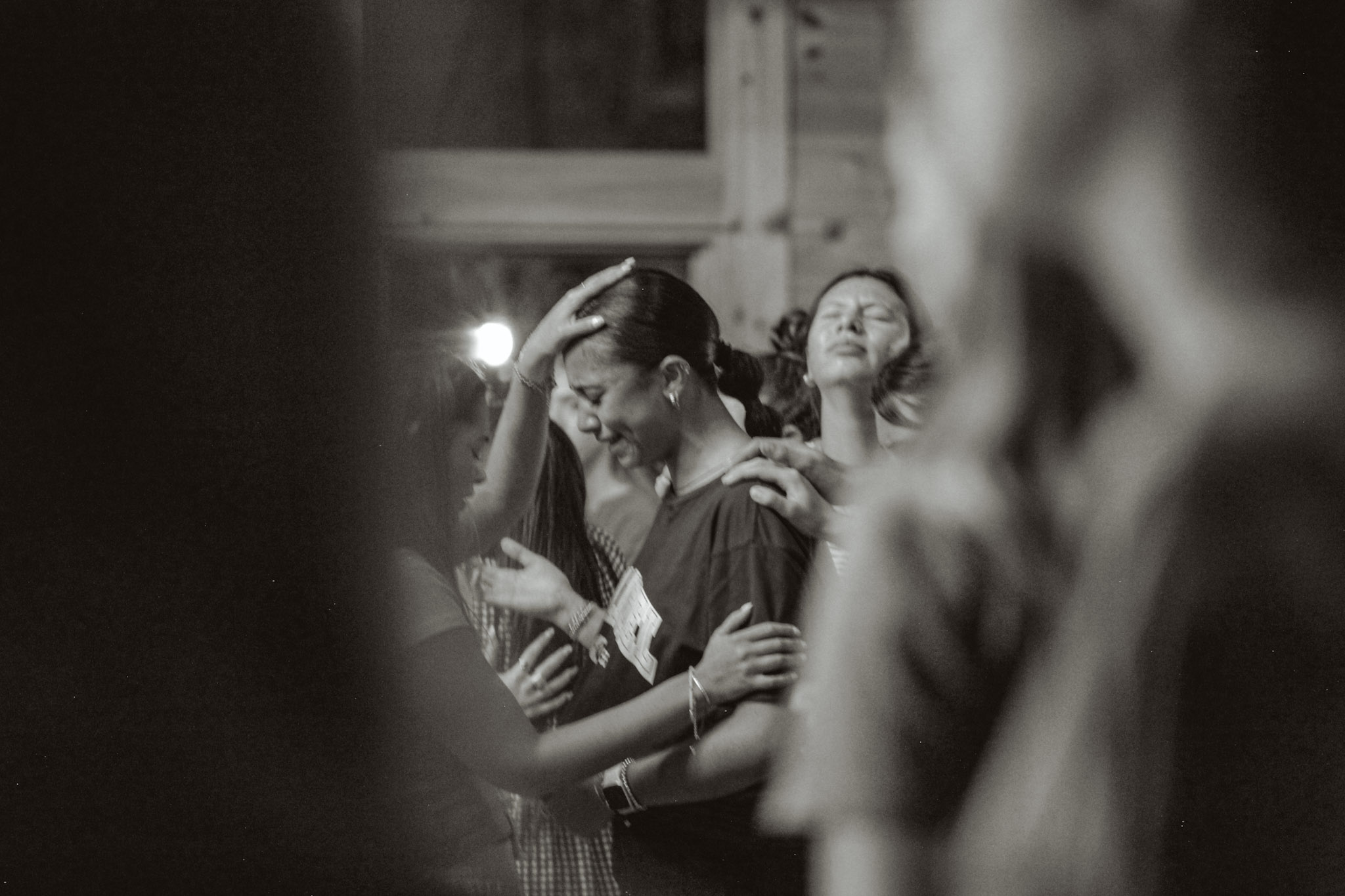 Friends laying hands on a young woman and praying over her as she weeps