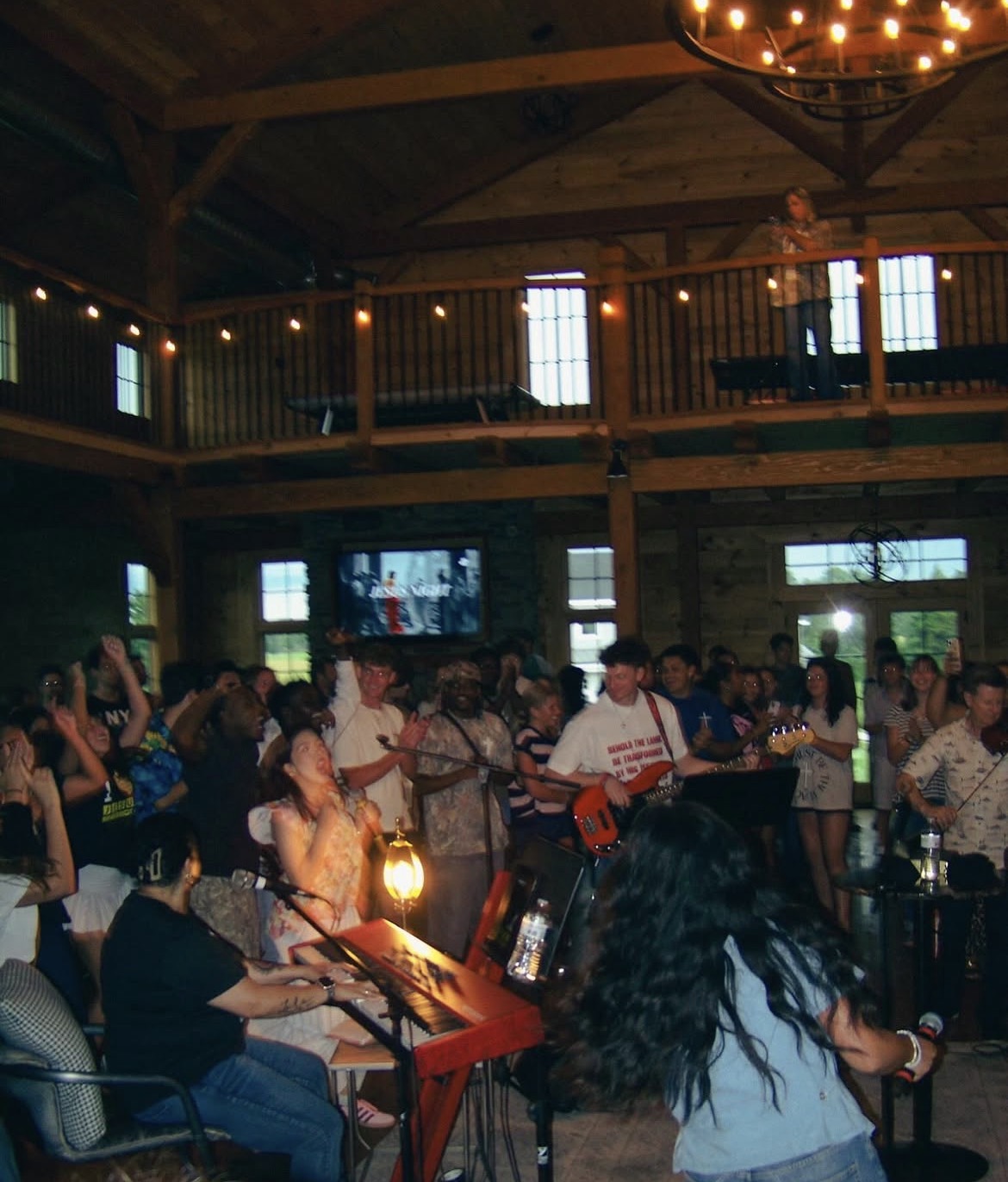 A crowded Jesus Place gathering worshiping together with live musicians