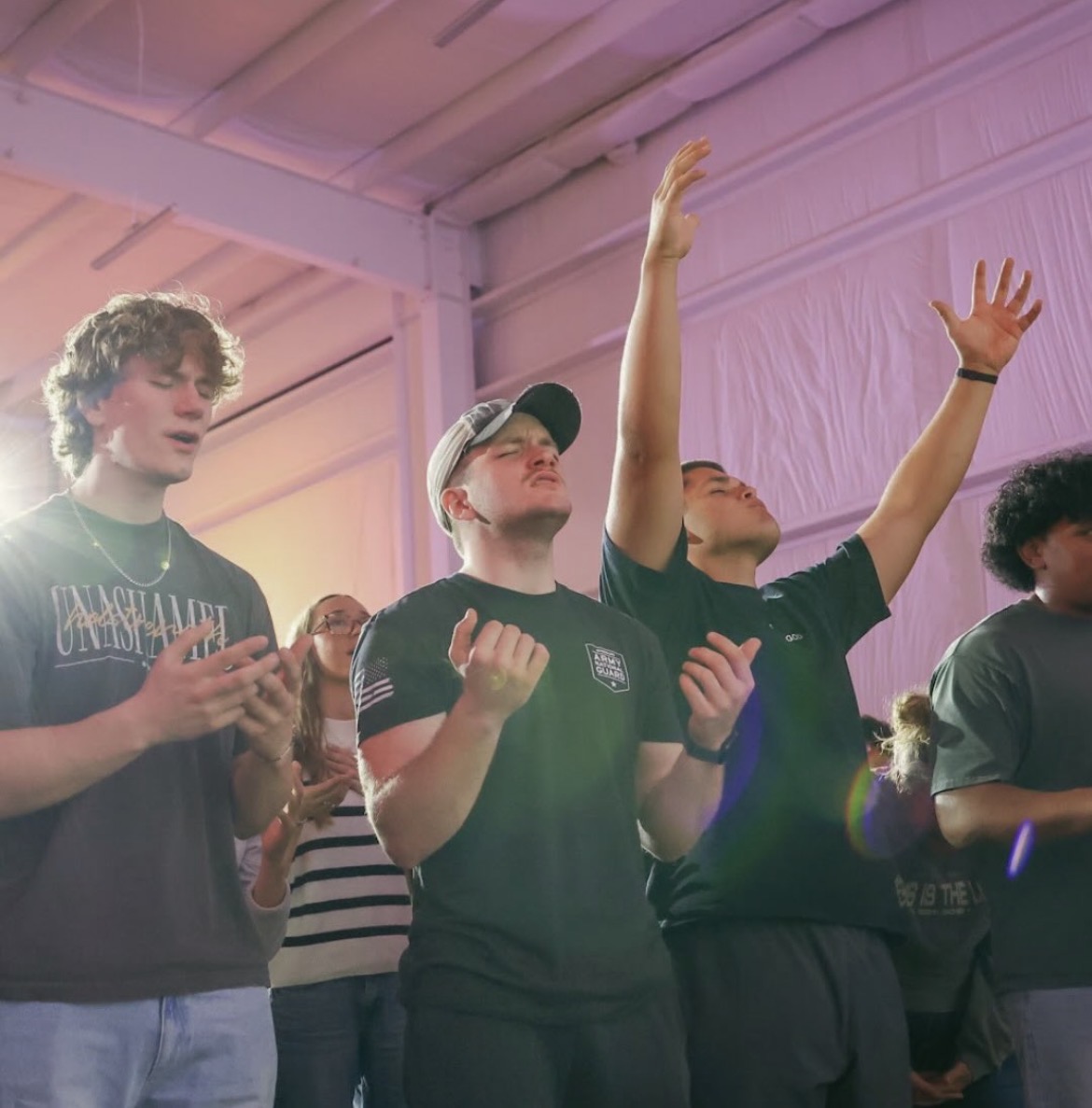 Young adults praying and raising their hands during worship
